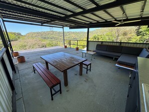 An outdoor patio with a wooden table, benches, a sofa, and potted plants. - Private Pool-River Refuge near San Jose (San Pablo)