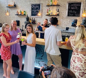 A bar area with a chalkboard menu, bottles of alcohol, and a camera capturing the scene.