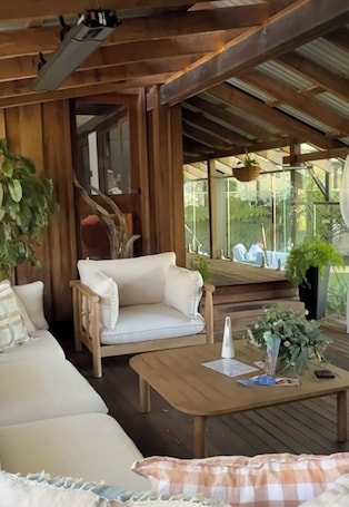 A wooden deck with a sofa, a coffee table, and potted plants.. Amaroo Retreat & Spa
