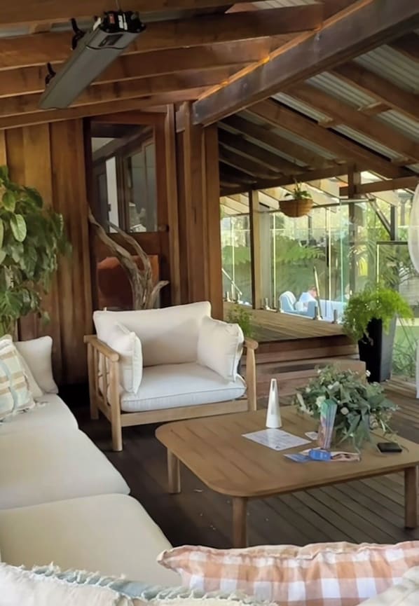 A wooden deck with a sofa, a coffee table, and potted plants.