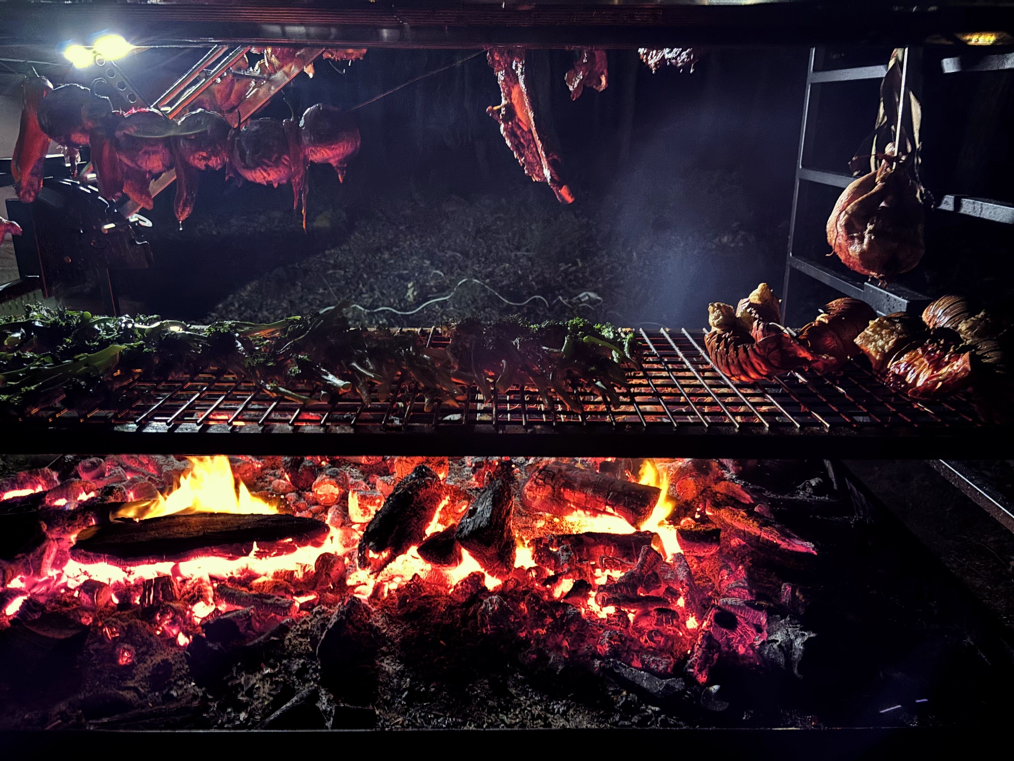 Un barbecue où différentes sortes de viandes et de légumes sont en train de cuire sur une flamme nue.
