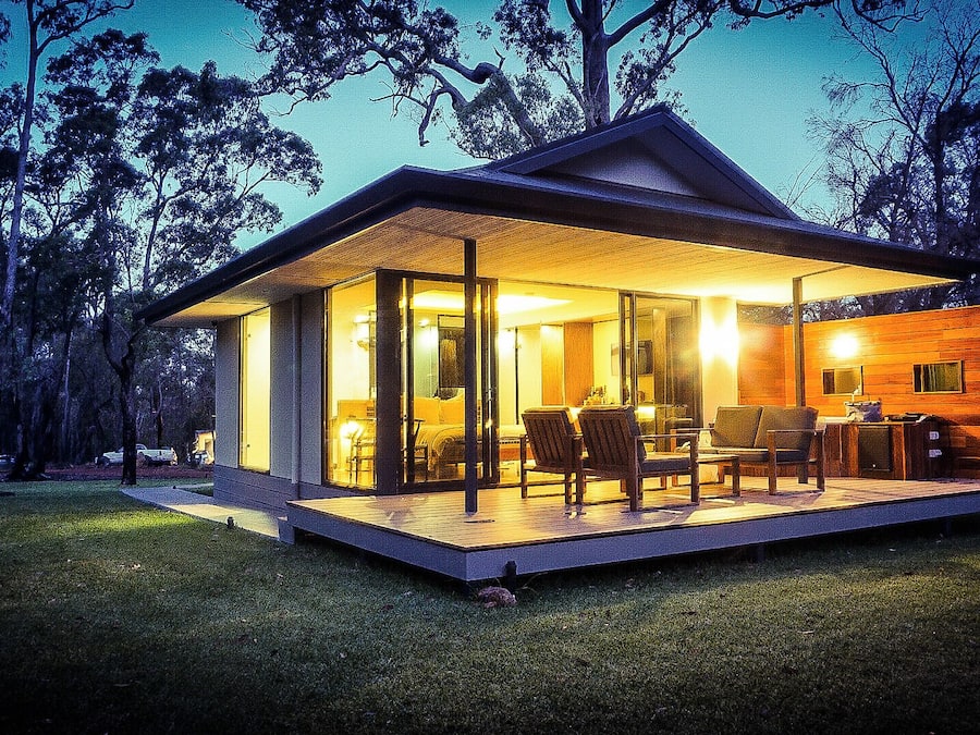 Una casa moderna con un porche de vidrio, un comedor y una cocina visible.