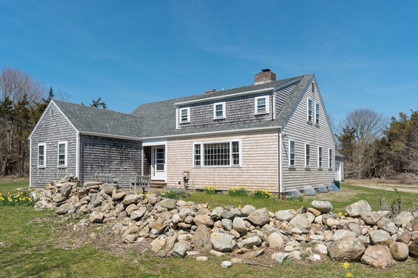 A two-story house with a stone foundation, a large front porch, and a garage.