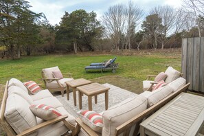 Un patio con mobiliario exterior, que incluye un sofá, sillas y una mesa.
