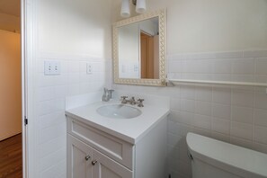 A bathroom with a white sink, mirror, and toilet.