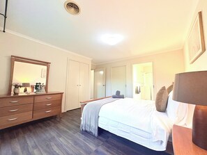 A bedroom with a bed, dresser, mirror, and a door leading to a bathroom.