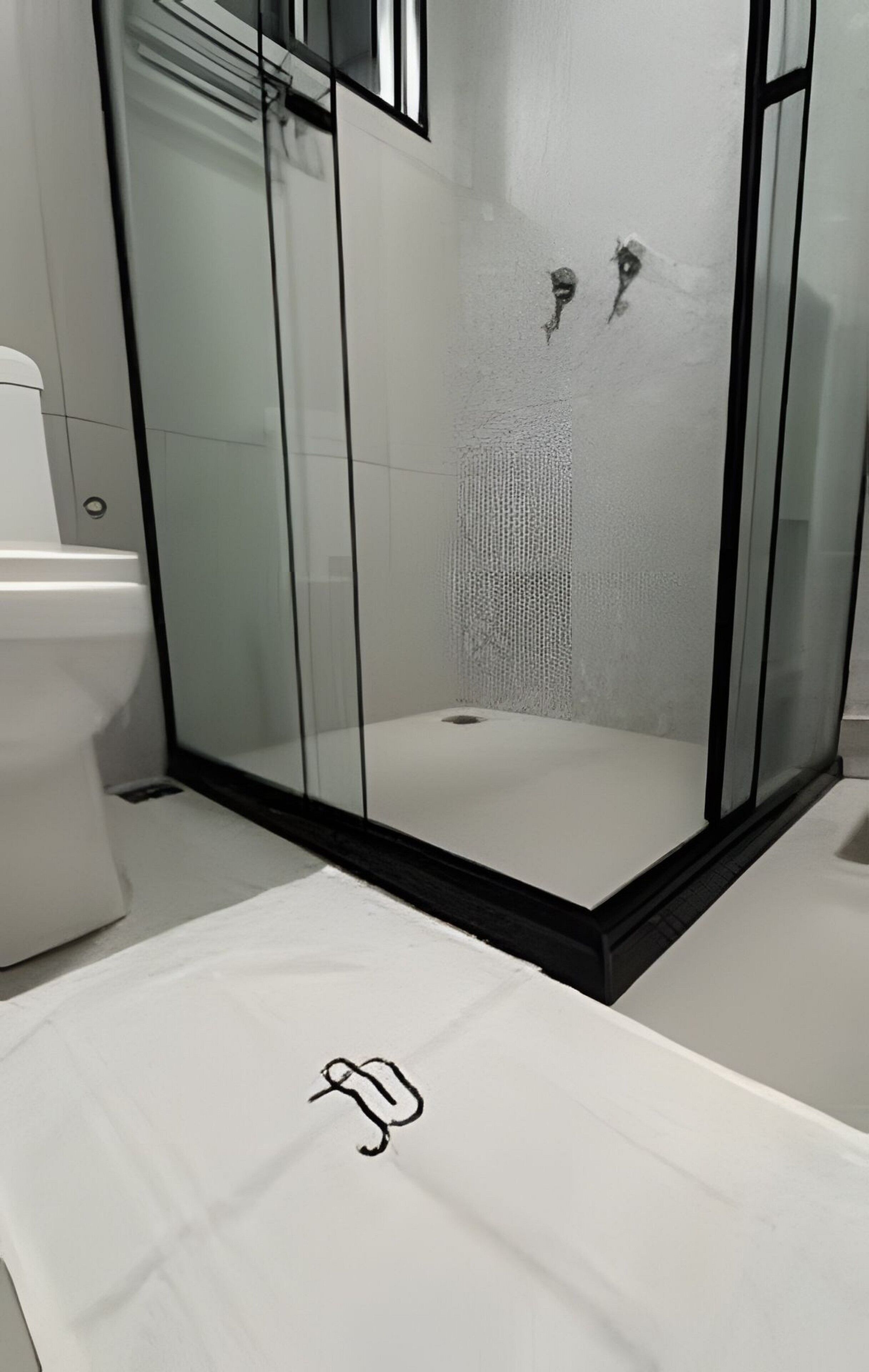 A modern bathroom with a glass-enclosed shower, a white toilet, and a marble-topped sink.