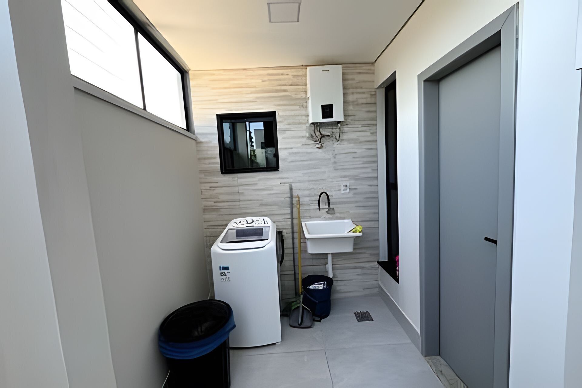 A compact bathroom with a washing machine, sink, and a small window.
