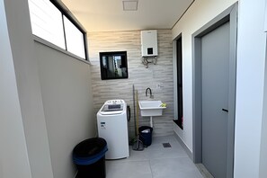 A compact bathroom with a washing machine, sink, and a small window.
