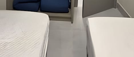 Une pièce de taille modeste comprenant un lit, une armoire avec espace pour suspendre des vêtements et une porte donnant sur une autre pièce.