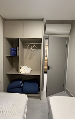 A compact room with a bed, a wardrobe with hanging space, and a door leading to another room.