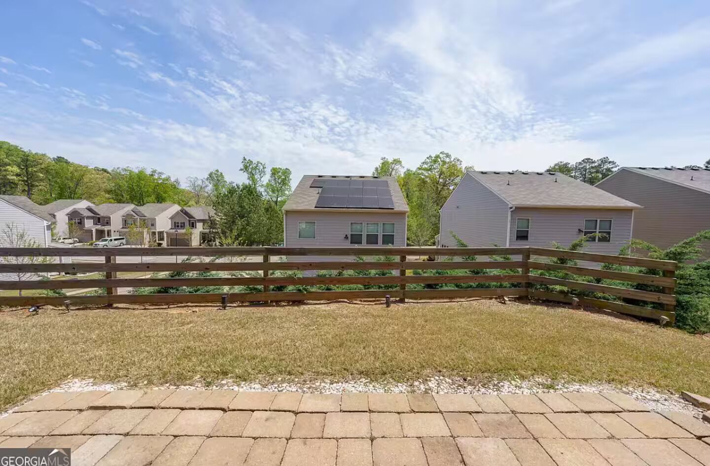 A residential area with houses, a wooden fence, and a paved walkway.
