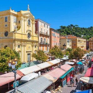 A street with colorful buildings, a clock tower, and market stalls. - Nice Old Town Studio, Sleeps 2 (Nice)