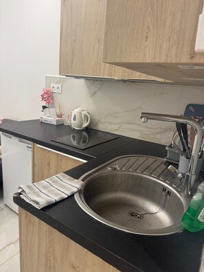 A kitchen with a stainless steel sink, a black countertop, and wooden cabinets. - Nice Old Town Studio, Sleeps 2 (Nice)