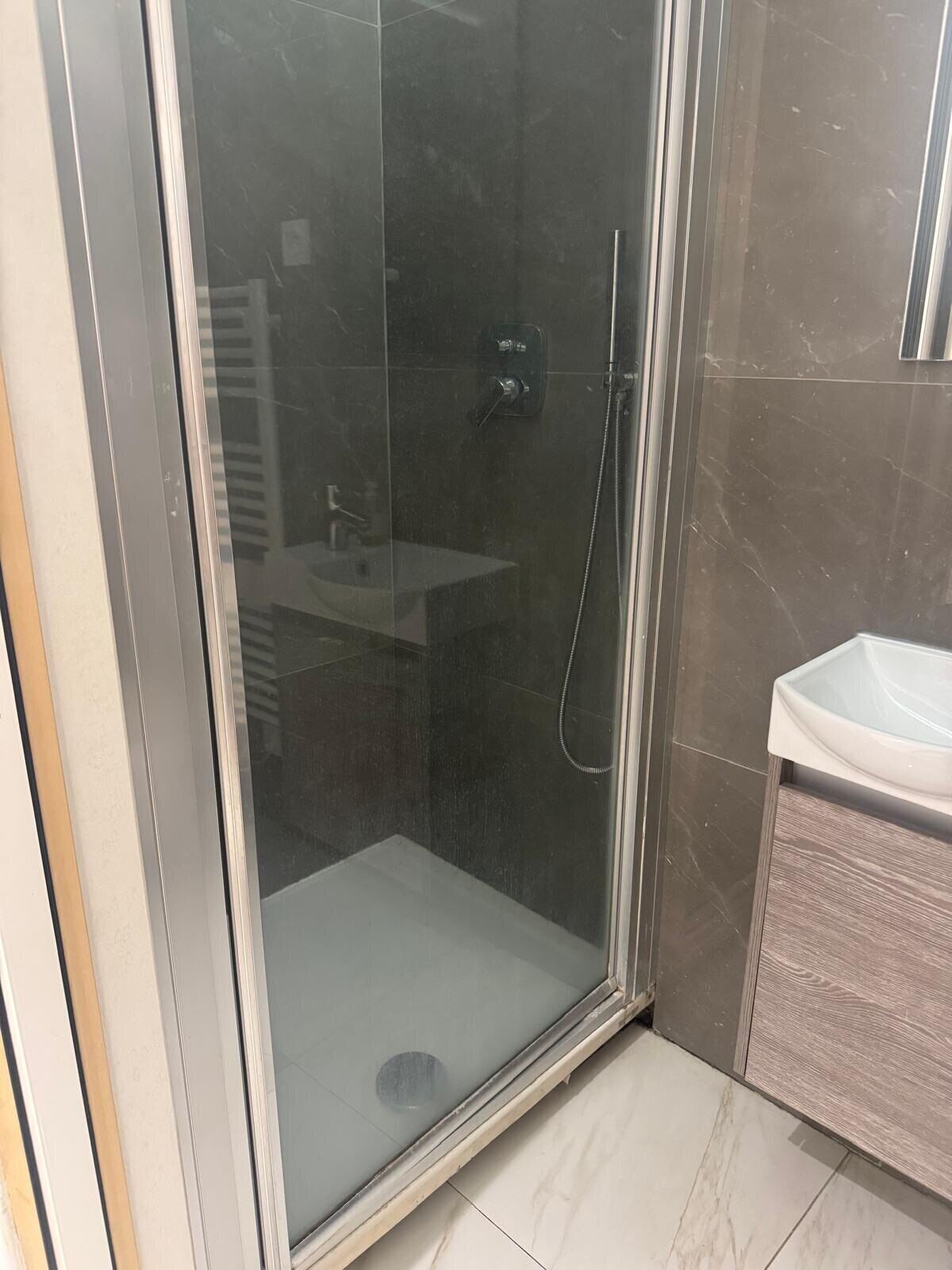 Une salle de bain moderne avec une douche à parois de verre, un lavabo et un meuble-lavabo.