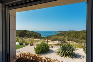 Ein Balkon mit Blick auf eine Küstenlandschaft, einschließlich Bäumen, einem Gewässer und einer entfernten Küstenlinie.