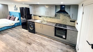 A compact kitchen with a washing machine, a stove, and a sink. - Studio - Sleeps 3 - AirCon - Parking - Pets (Northolt)