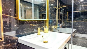 A bathroom with a white sink, gold faucet, and a large mirror with a gold frame. - Studio - Sleeps 3 - AirCon - Parking - Pets (Northolt)