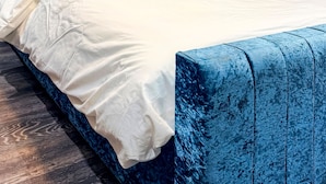 A modern bedroom with a blue headboard, a white bedspread, and a decorative wall piece. - Studio - Sleeps 3 - AirCon - Parking - Pets (Northolt)