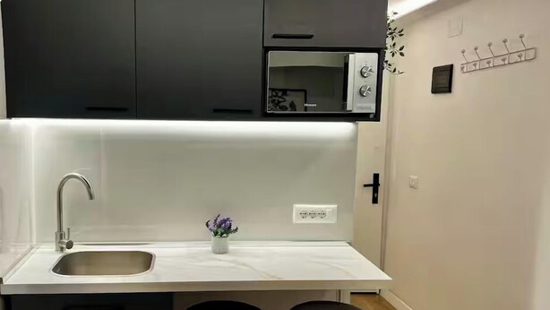 A compact kitchen with a sink, a small countertop, a microwave, and two stools. - Dajti National Park House, Sleeps 7 with AirCon (Tirane)