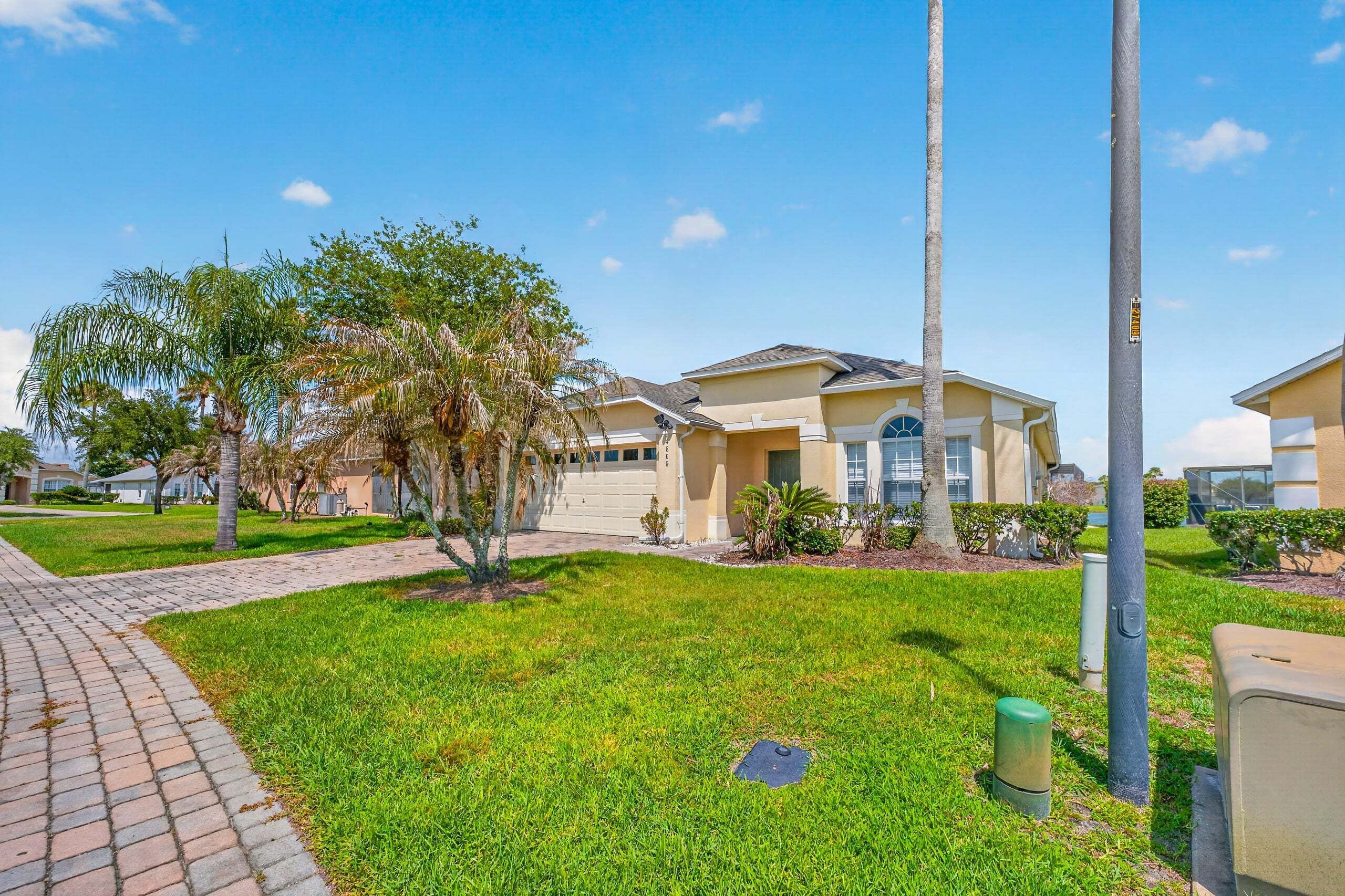 A residential area with houses, a paved walkway, and a grassy lawn.