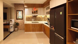 Eine moderne Küche mit Marmorarbeitsplatte, einem schwarzen Kühlschrank, Holzschränken und einem Blumentopf.