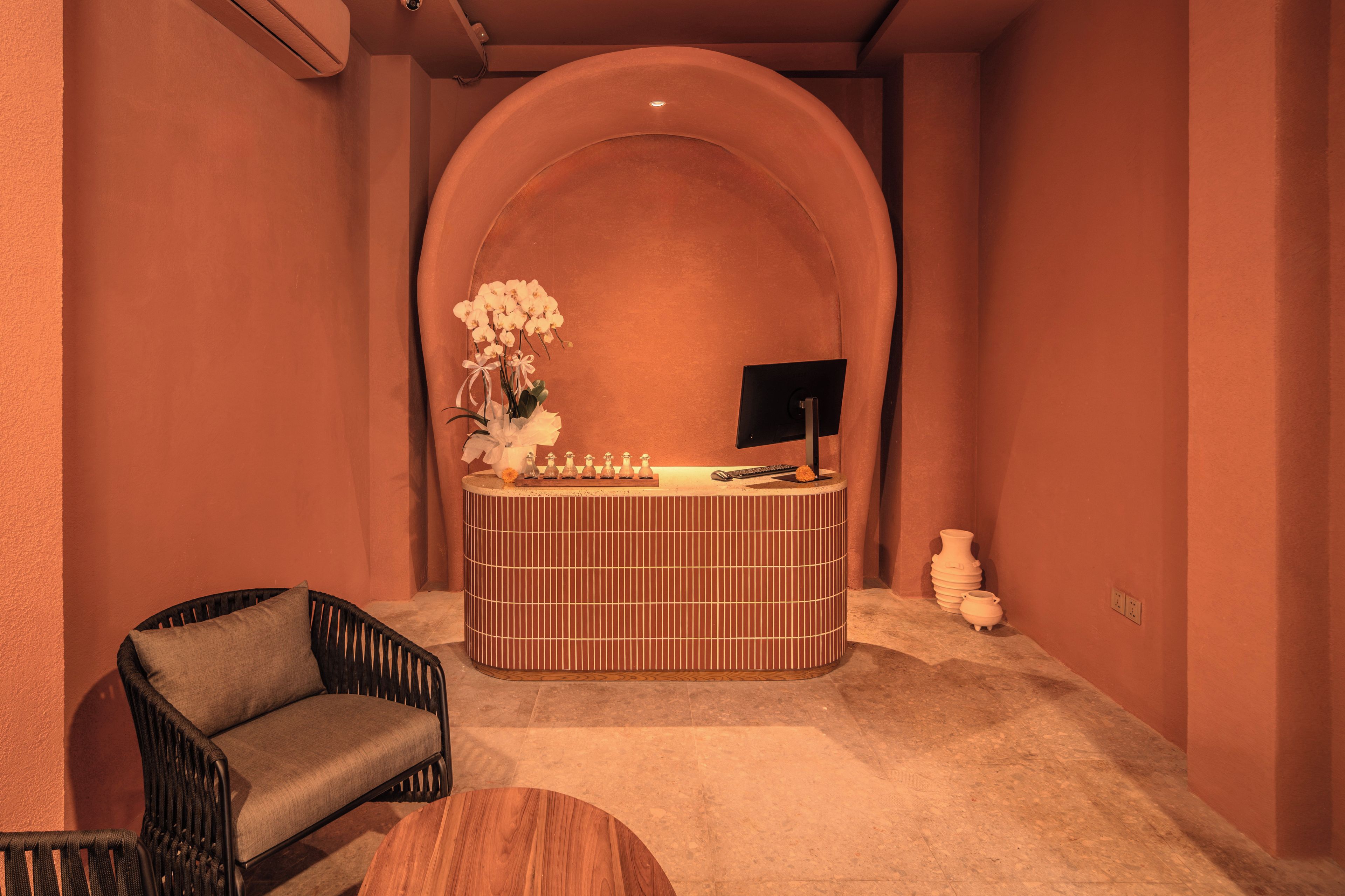 A reception area with a curved wall, a reception desk, a chair, and a small table.