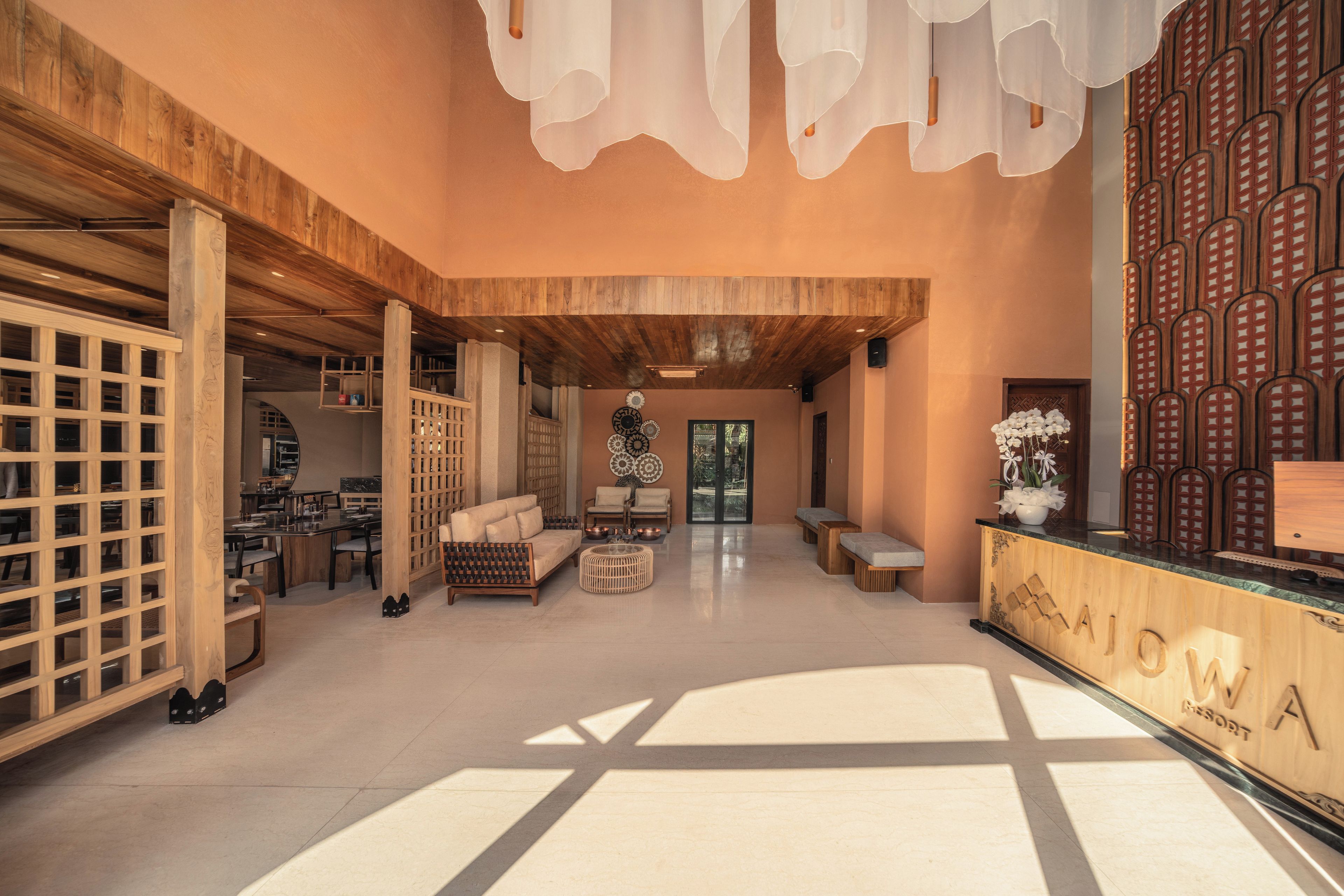A spacious lobby with a wooden reception desk, seating area, and a view of the outdoors.