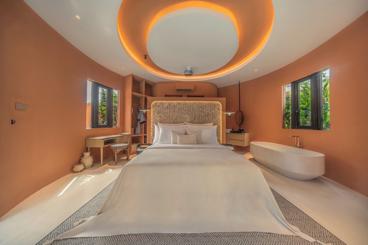Een moderne slaapkamer met een groot bed, een ingebouwd bad en een rond plafondlamp.