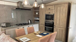 Una cocina moderna con estufa a gas, horno y microondas, armarios de madera y un comedor con mesa y sillas.