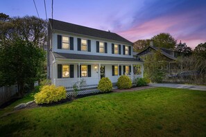 A two-story house with a porch, a driveway, and a well-maintained lawn. - Cape Cod Home Near 3 Beaches (Cotuit)