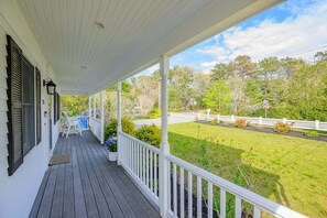 A covered porch with a view of a road and greenery. - Cape Cod Home Near 3 Beaches (Cotuit)