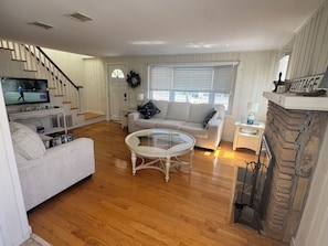 Una sala de estar con chimenea, televisión, sofá, mesa de centro y una escalera.