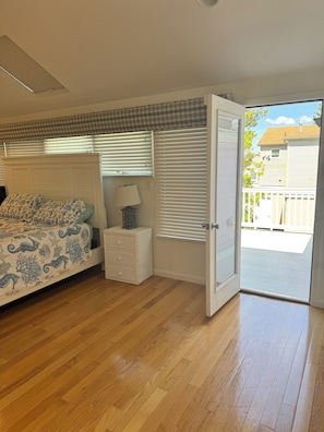 Un dormitorio con cama, mesita de noche, lámpara y vistas al exterior.