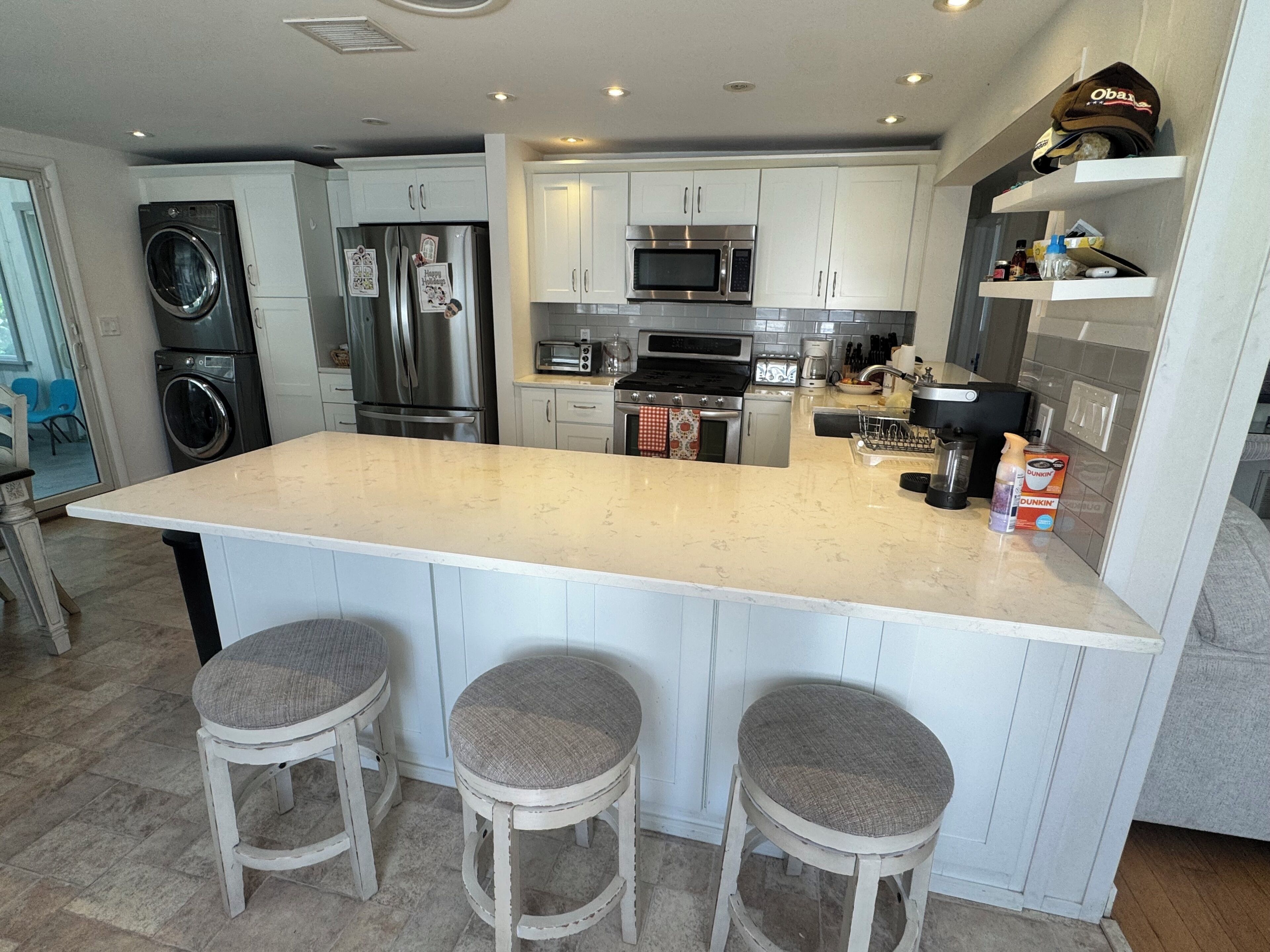 A modern kitchen with a large island, stainless steel appliances, and bar stools.