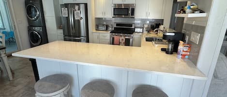 A modern kitchen with a large island, stainless steel appliances, and bar stools.