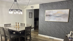 A dining area with a wooden table and chairs, a chandelier, and a framed painting on the wall. - Lake House Retreat with Lakeside Hot Tub (Roxboro)