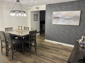 A dining area with a wooden table and chairs, a chandelier, and a framed painting on the wall. - Lake House Retreat with Lakeside Hot Tub (Roxboro)