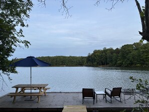 Un espace de pique-nique au bord du lac, équipé d’une table, de chaises et d’un parasol.