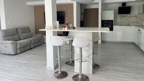 Moderni keittiö, jossa on valkoiset kaapit, marmoripintainen välitila ja sisäänrakennettu uuni.