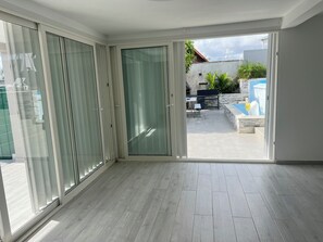 Ein Zimmer mit einer Schiebetür zu einer Terrasse im Freien mit Pool und Sitzgelegenheiten.