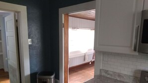 Een keuken met witte kasten, een afvalbak van roestvrij staal, een marmeren aanrechtblad en uitzicht op een eetruimte.