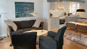 Moderni olohuone, jossa on sohva, nojatuoleja, sohvapöytä ja taulu seinällä.