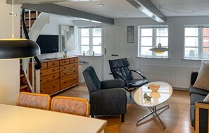 A modern living room with a sofa, armchairs, a coffee table, a TV, and a fireplace. - Cozy home in Rudkøbing with WiFi (Rudkøbing)