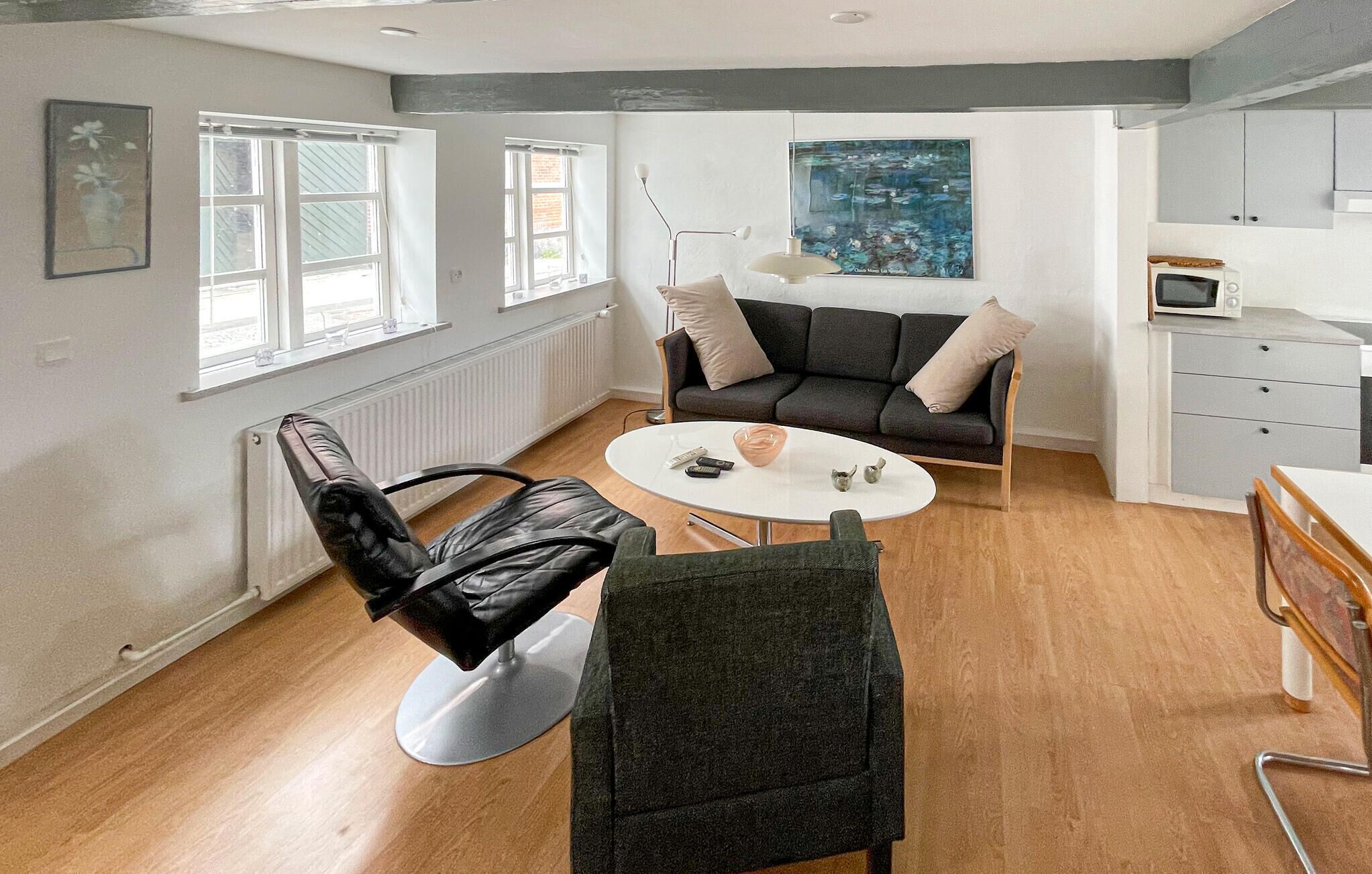Una sala moderna con un sofá, una mesa de centro, una silla y un cuadro en la pared.