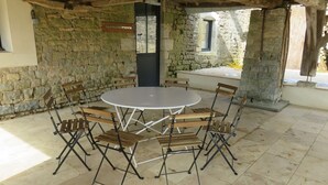 Een kamer met stenen muren, een ronde tafel en opklapbare stoelen.
