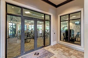 Ein Fitnessstudio mit Trainingsgeräten, einem Fischgrätparkett und einer Tür mit Fensterteil.