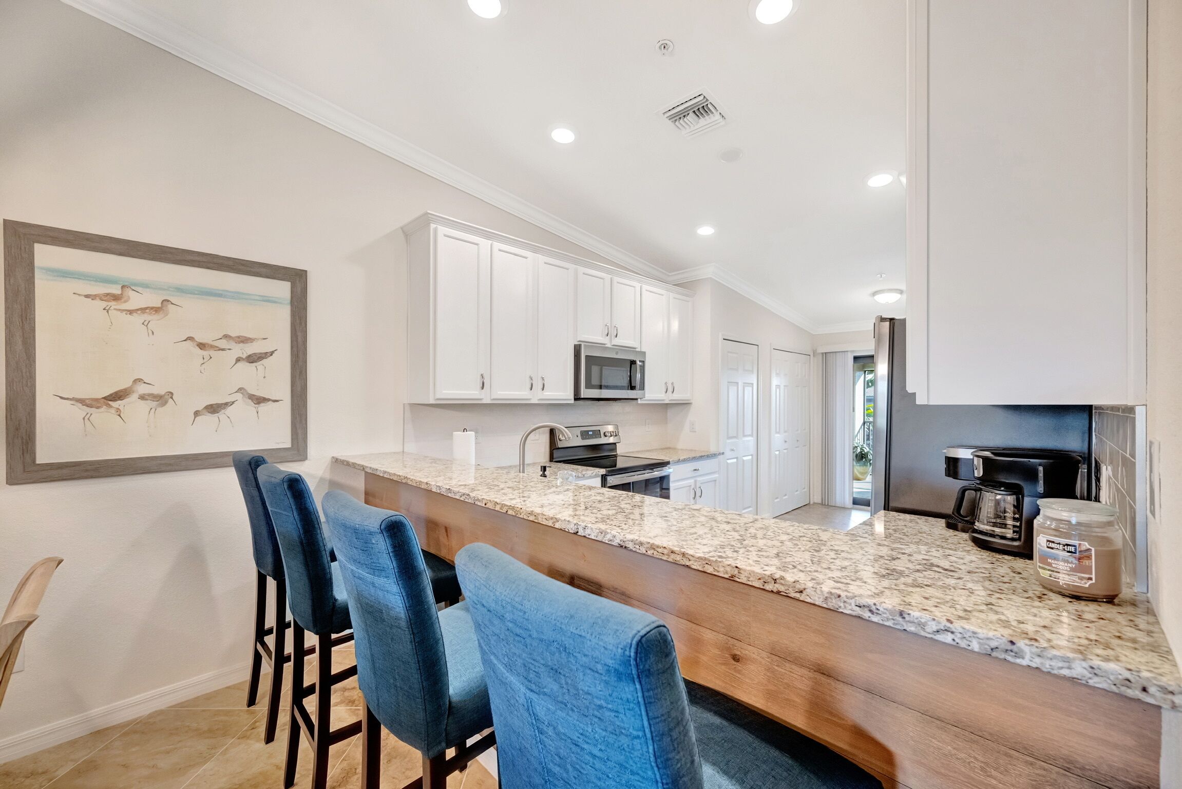 A kitchen with white cabinets, a granite countertop, and a coffee maker.