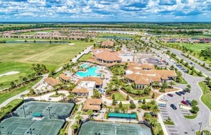 Ein Golfplatz, ein Schwimmbad, Tennisplätze und ein großes Gebäude mit einem Strohdach.