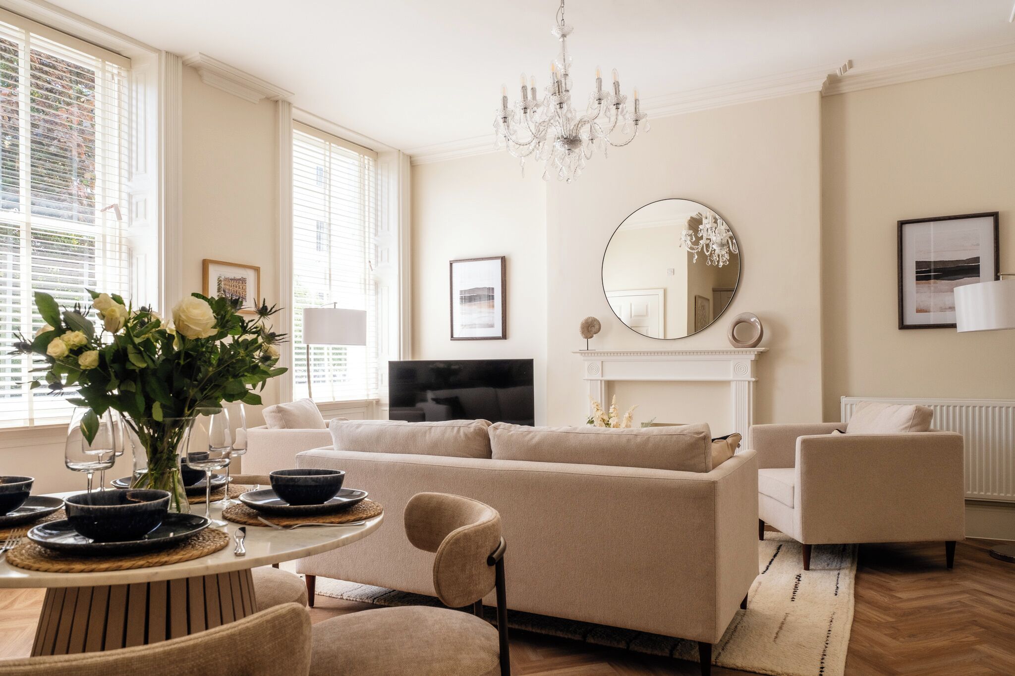A living room with a sofa, chairs, a TV, a fireplace, and a chandelier.
